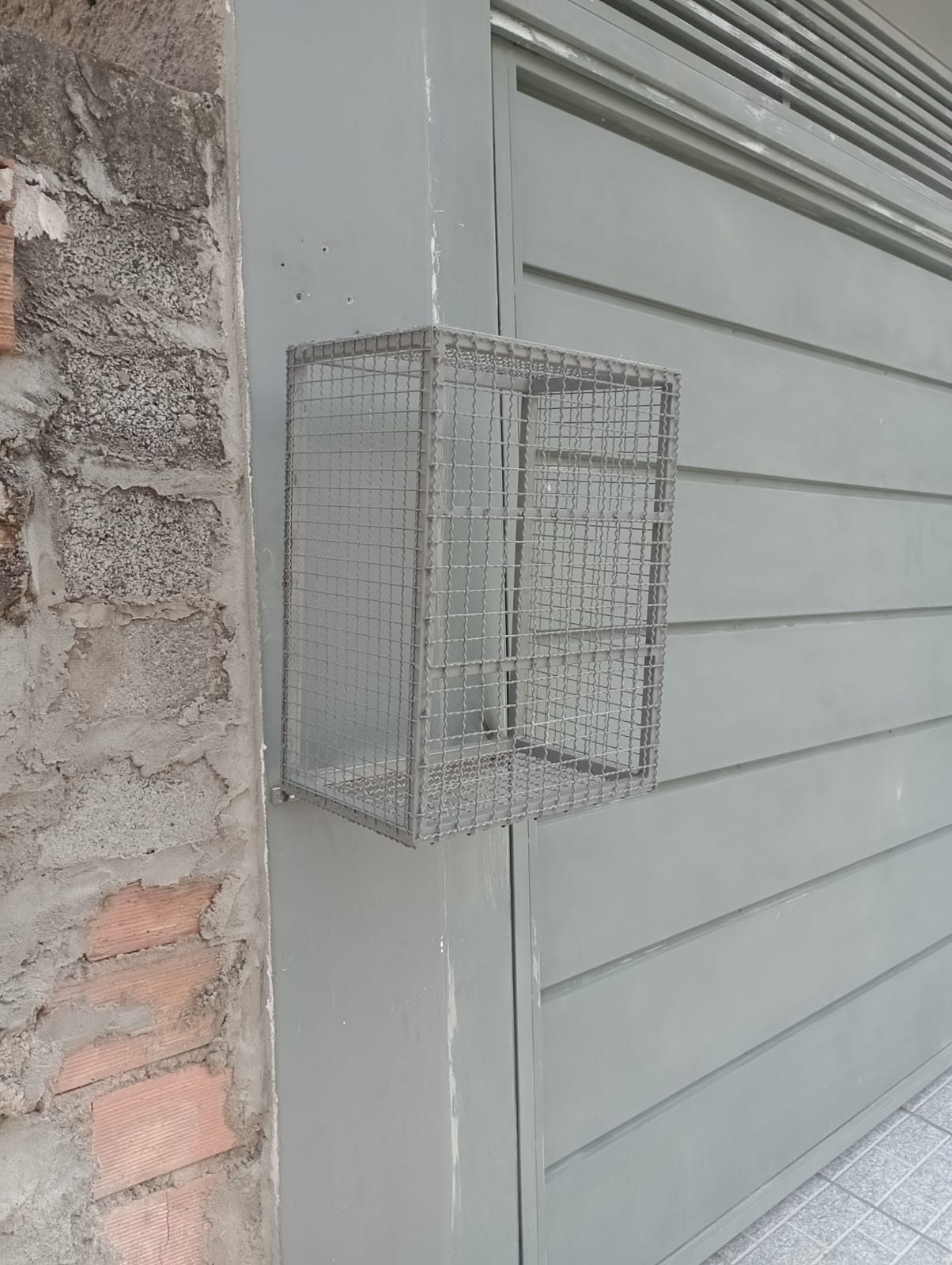 Lixeira de parede em tela metálica instalada na fachada no Jardim Santo Eduardo, Embu das Artes