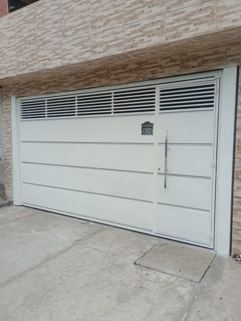 Portão basculante branco com ventilação superior instalado em garagem em Itapecerica da Serra