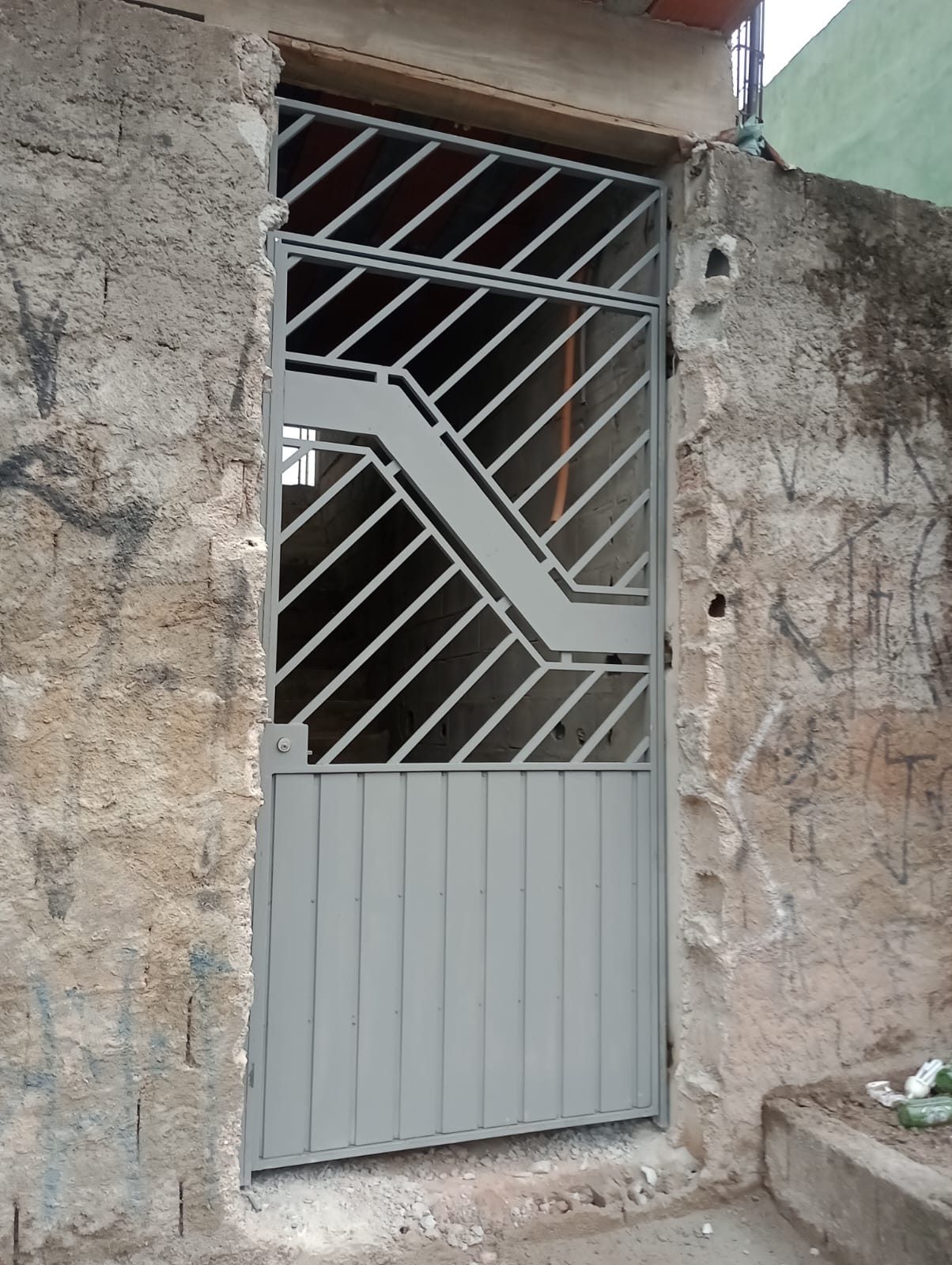 Portão social de ferro cinza com grade decorativa instalado no Valo Velho, Zona Sul de São Paulo