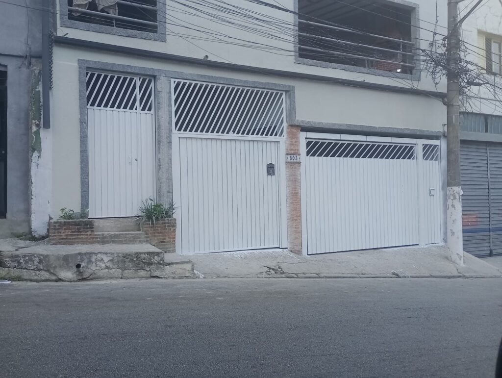 Dois portões de garagem e um portão social pintados de branco no Jabaquara, Zona Sul de São Paulo