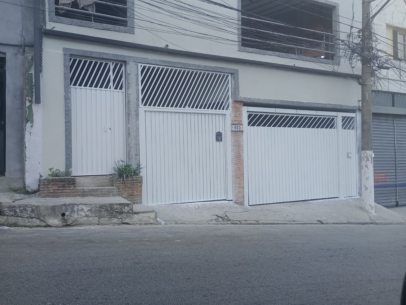 Dois portões de garagem e um portão social pintados de branco no Jabaquara, Zona Sul de São Paulo